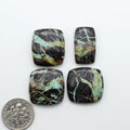 Black Jack turquoise cabochons, blue-green color with black matrix, polished stones on a white background with a US dime for scale