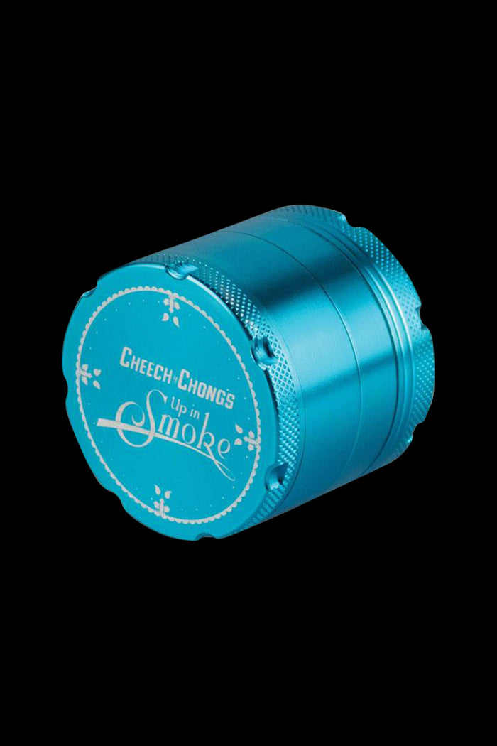 A slightly angled, close-up view of the Cheech & Chong's Up In Smoke Grinder, showcasing its metallic, multi-tiered construction.