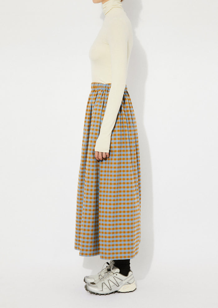 A woman wearing a gingham skirt in blue and brown.
