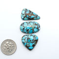 Pressed Turquoise nugget cabochons, composite material with a blue color and dark matrix on a white background, with a US dime for scale.