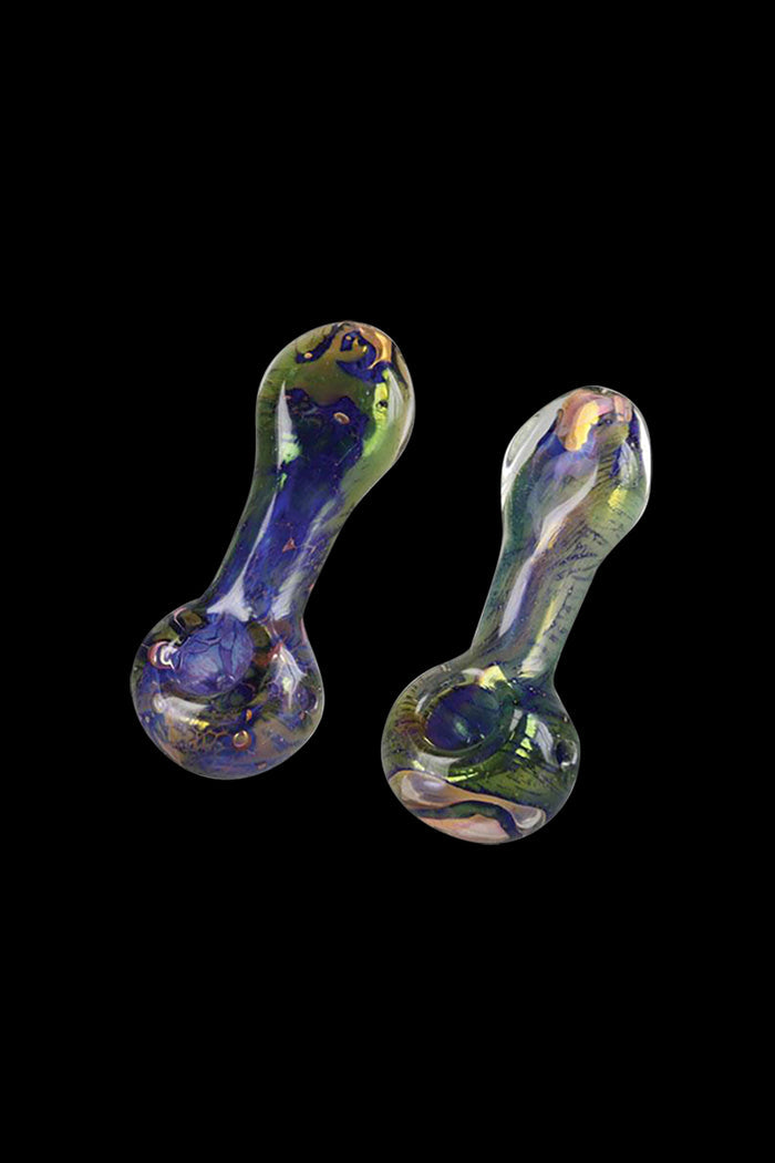 A close-up, angled view of the Spattered Fumed Hand Pipe, showcasing its colorful, glass construction against a dark background.